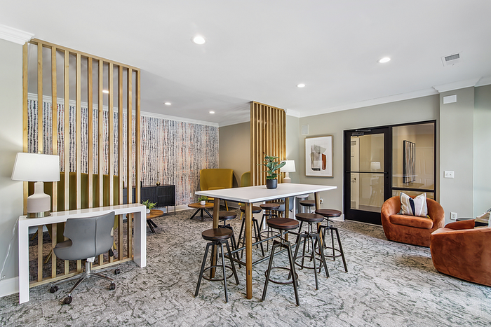 Modern and inviting apartment clubhouse lounge with stylish furnishings, featuring cozy seating areas, wooden partitions, and a contemporary workspace.