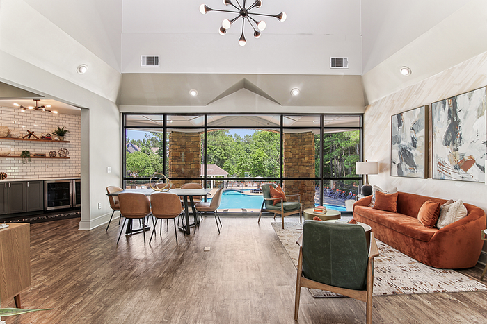 Bright and airy clubhouse with modern furnishings and large windows overlooking a pool; elegant dining area and stylish brick kitchen complement the inviting atmosphere.
