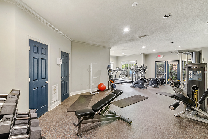 Modern fitness center with state-of-the-art gym equipment, including weight machines, treadmills, and free weights in a spacious, well-lit environment.