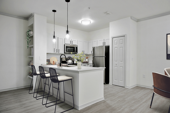 Modern kitchen with sleek white cabinetry, stainless steel appliances, and a chic breakfast bar with pendant lighting.