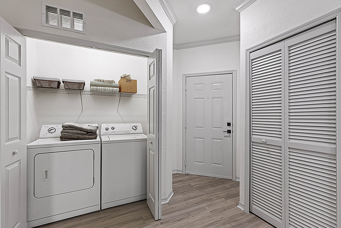 Bright and welcoming laundry nook with washer and dryer, featuring organized shelving and soft lighting, perfect for convenient home living.