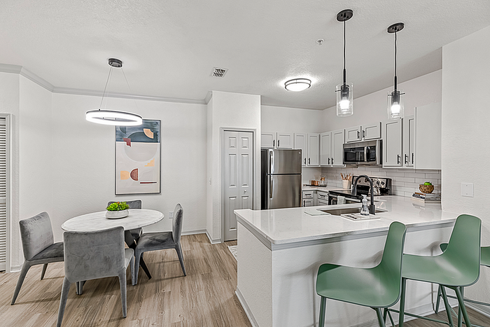 Modern kitchen and dining area featuring sleek cabinetry, stainless steel appliances, and an elegant marble dining table with stylish seating.