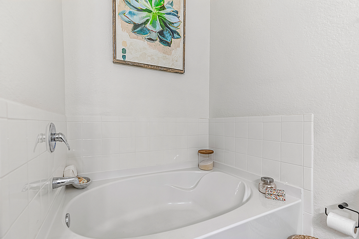 Elegant bathroom featuring a pristine white bathtub, tasteful wall art, and chic decor for a relaxing oasis.