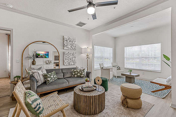 Bright and inviting living room with modern decor, featuring a comfortable sofa, stylish accent chairs, and large sunlit windows.