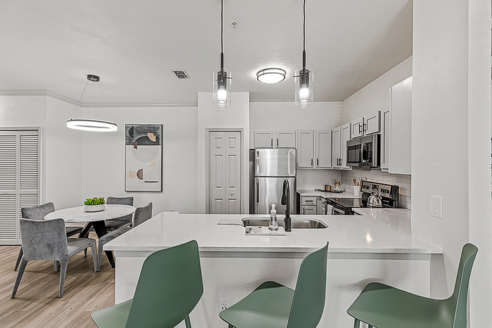 Modern kitchen and dining area with sleek cabinetry, stainless steel appliances, and elegant pendant lighting, perfect for contemporary living.