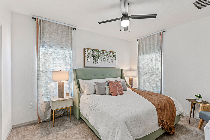 Inviting bedroom with a plush green upholstered bed, elegant lighting, and chic decor for a cozy atmosphere.