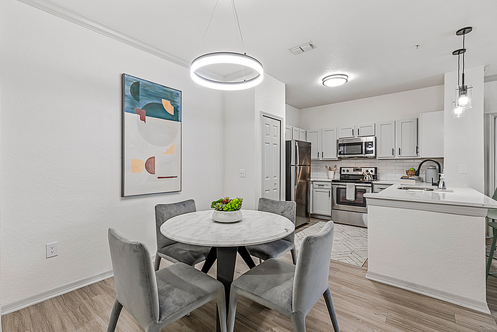 Modern apartment interior showcasing a sleek kitchen with stainless steel appliances, stylish dining area with a marble table, and contemporary lighting.