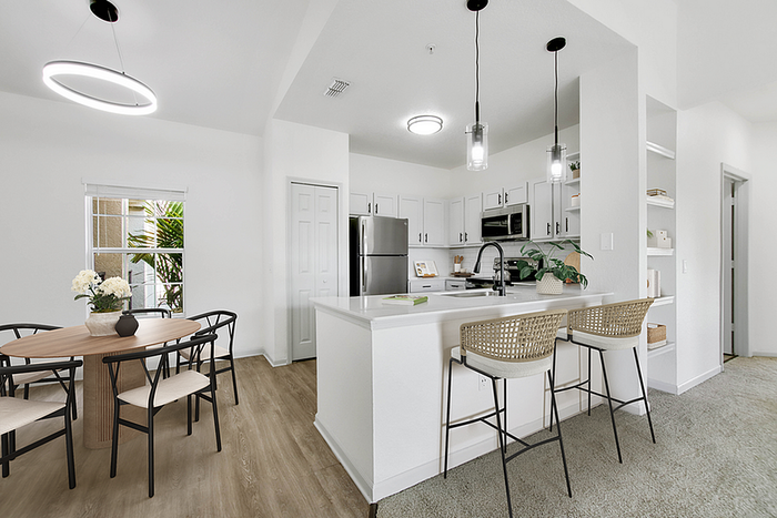 Bright open-concept kitchen and dining area with modern furnishings, featuring sleek pendant lighting and a charming breakfast bar.