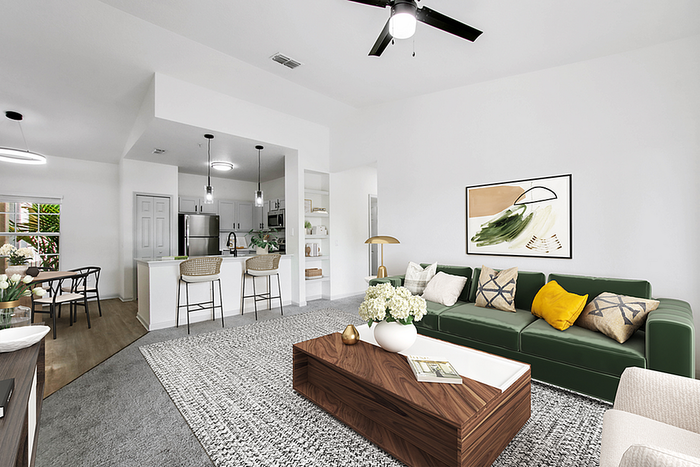 Contemporary living area showcasing a cozy green sofa, elegant coffee table, open kitchen with bar stools, and a dining area with abundant natural light.
