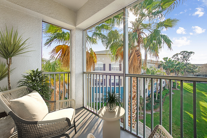Charming apartment balcony with cozy seating and lush palm tree views, perfect for relaxing outdoors.