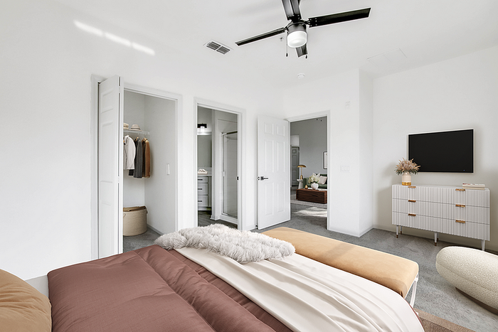 Bright and modern bedroom with cozy bedding, spacious closets, and a sleek ceiling fan.