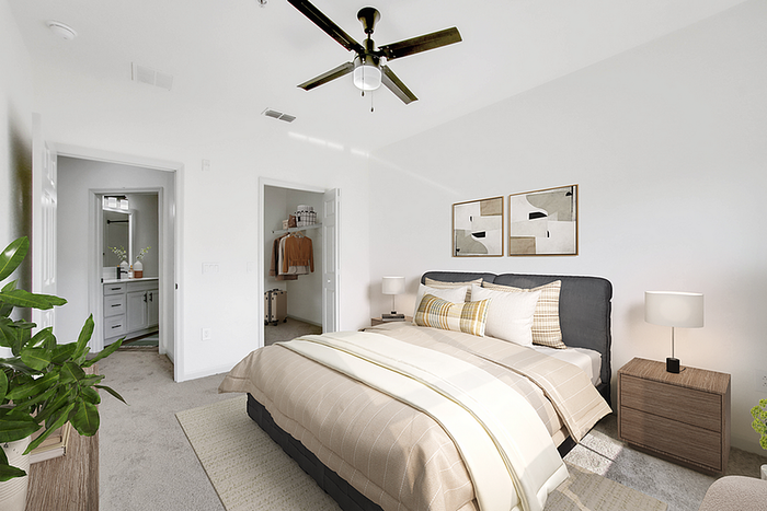 Bright and inviting bedroom with modern decor, featuring a plush bed, contemporary art, and sleek ceiling fan, complemented by a cozy carpet and natural light.
