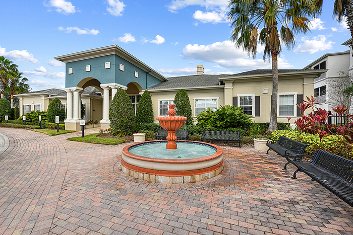 Elegant Leasing Office entrance with a beautiful red fountain, lush landscaping, and inviting pathways under a clear blue sky.