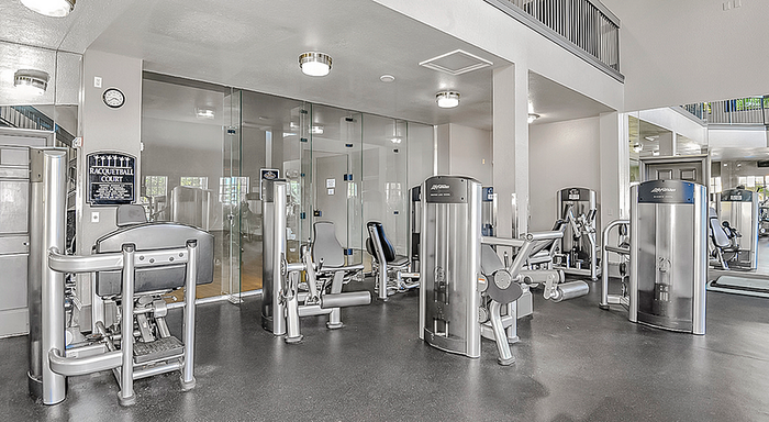 Modern fitness center equipped with state-of-the-art exercise machines and a glass-enclosed racquetball court.