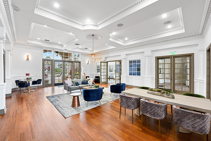 Elegant clubhouse space featuring modern furniture, stylish decor, and ample natural light with hardwood flooring and a unique ceiling design.
