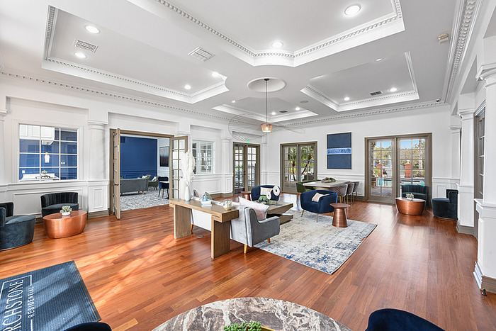 Elegant and spacious clubhouse area featuring polished hardwood floors, modern seating, and abundant natural light.