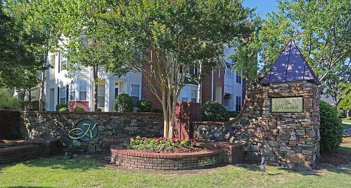 Charming apartment entrance with elegant stonework, lush greenery, and vibrant flower beds.