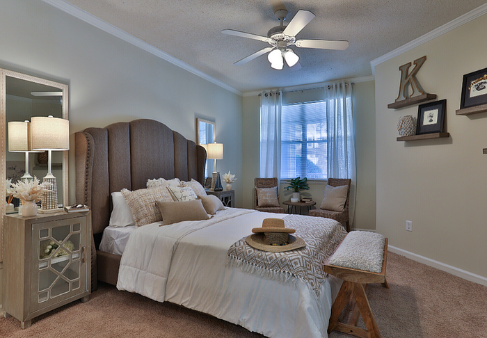 Elegant bedroom with plush bedding, chic decor, and natural light. Features cozy armchairs, stylish side tables, and a tasteful ceiling fan, creating a serene retreat.