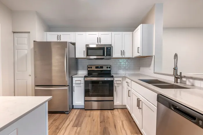 Modern kitchen equipped with stainless steel appliances, large countertops, a floating island, and ample lighting.