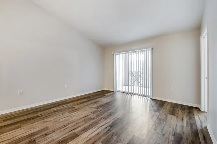 Spacious living room with ample room for seating, natural sunlight, and a large glass door.
