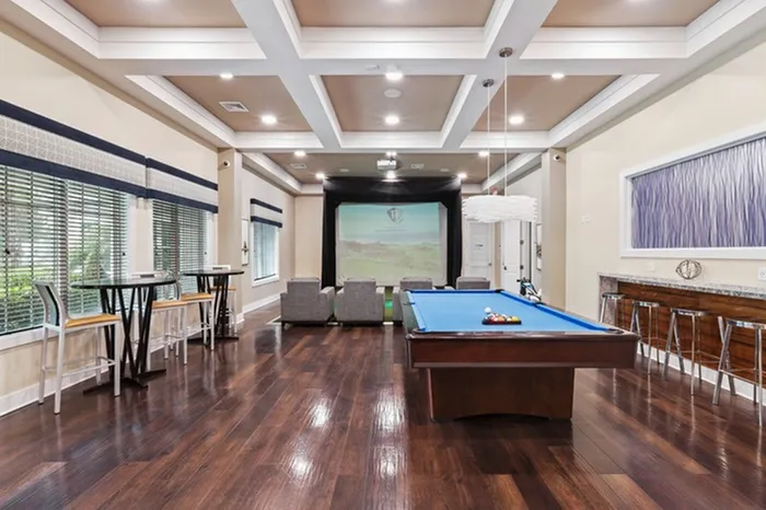 Game room with a billiard table and movie theater screen with reclining chairs at Lantower Asturia Apartments.