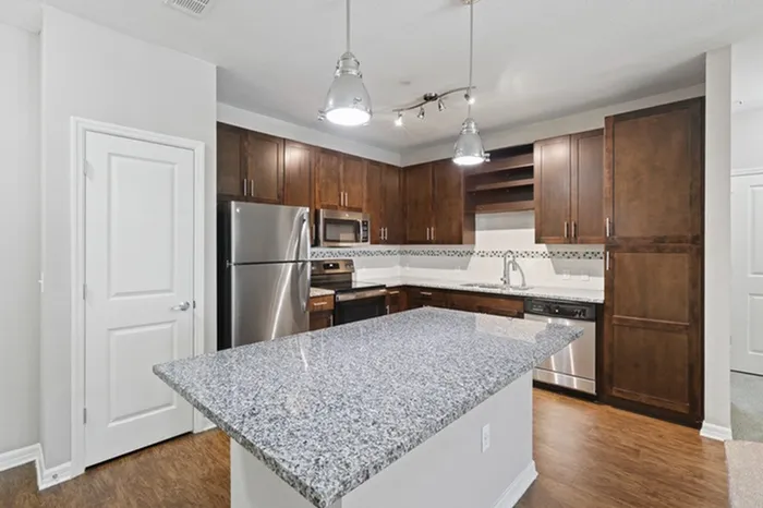 Kitchen with granite counters, wood plank floors, espresso custom cabinetry, stainless steel, energy efficient