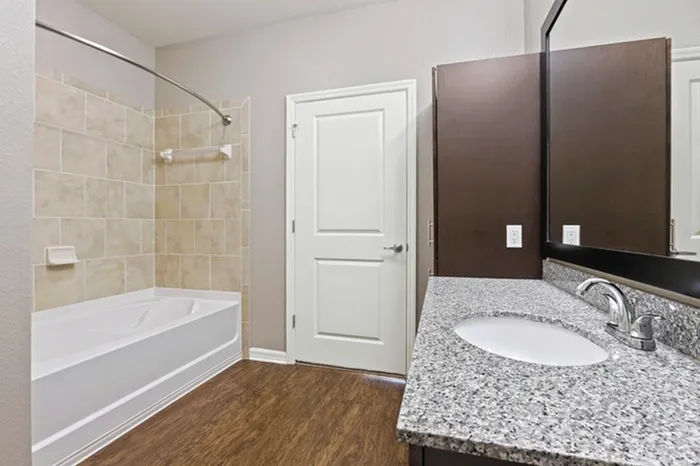 Bathroom with granite counters, wood plank floors, and soaking tub at Lantower Asturia.