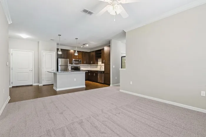 Energy-efficient kitchen with granite countertops, stainless steel appliances, and a kitchen island with the hard-wood floor living room the background with access to a balcony at Lantower Asturia.