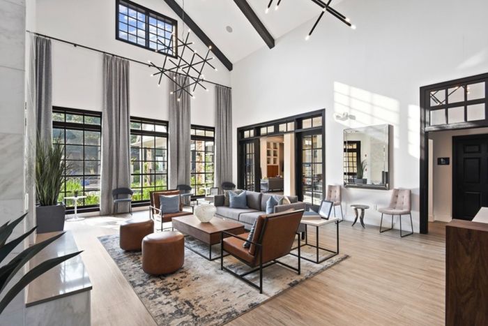 Spacious lounge area fit with brown chairs, cozy sofas, large window panes for natural lighting, and sound-tech floating plank floors in boardwalk finish at Lantower Round Rock