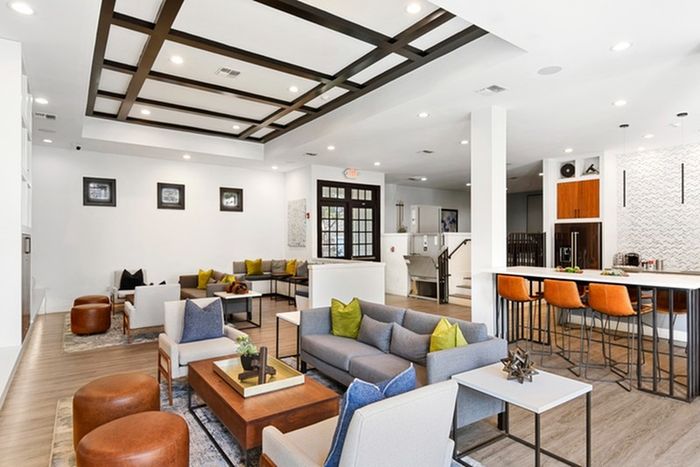 Large lounge area with groups of sitting areas, including sofas and couches surround coffee tables as well as elevated counters with stools, all in a bright lit room on sound-tech floating plank floors in boardwalk finish at Lantower Round Rock