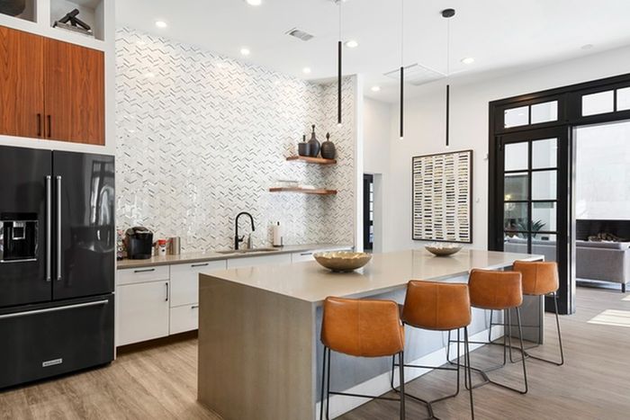 Modern kitchen finished with resilient quartz countertops, stainless steel Whirlpool appliances, and wood-style cabinets above the fridge as well as communal seating at Lantower Round Rock