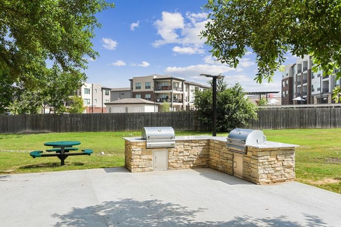 Spacious fenced in, grass outdoor area paired with a circular table and cement floored grilling area at Lantower Round Rock