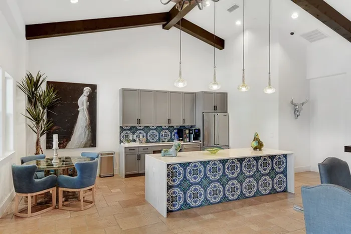 Modern clubhouse lobby with comfortable seating, premium finishes, and a modern kitchen with stainless steel appliances and mosaic tiling at Lantower Ambrosio Apartments.