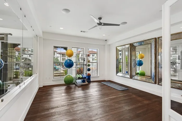 Yoga studio with yoga equipment, ceiling fan for cooling, mirrors on the wall and natural lighting at Lantower Ambrosio Apartments