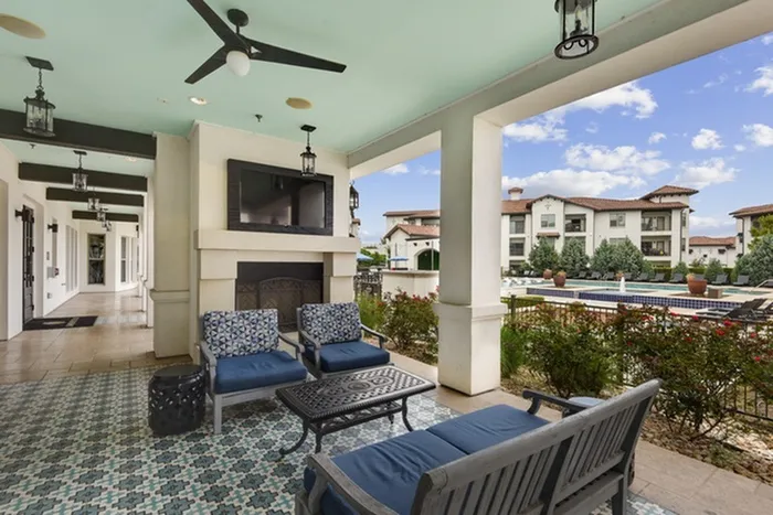 Resort style lounge area with outdoor seating, outdoor television, fireplace, and swimming pool access at Lantower Ambrosio Apartments