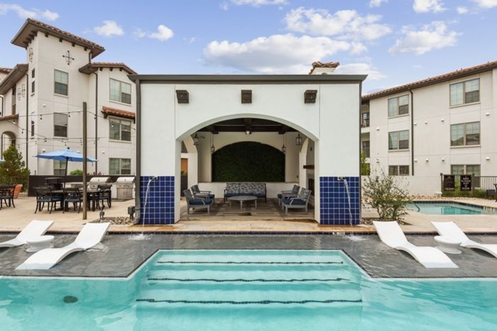 Resort-style pool with a shaded lounge area, deck and ample relaxing seating at Lantower Ambrosio Apartments.
