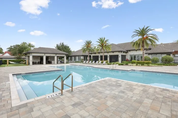Resort-style pool with sundeck, lounge chairs, a covered veranda, and palm trees at Lantower Grande Pines