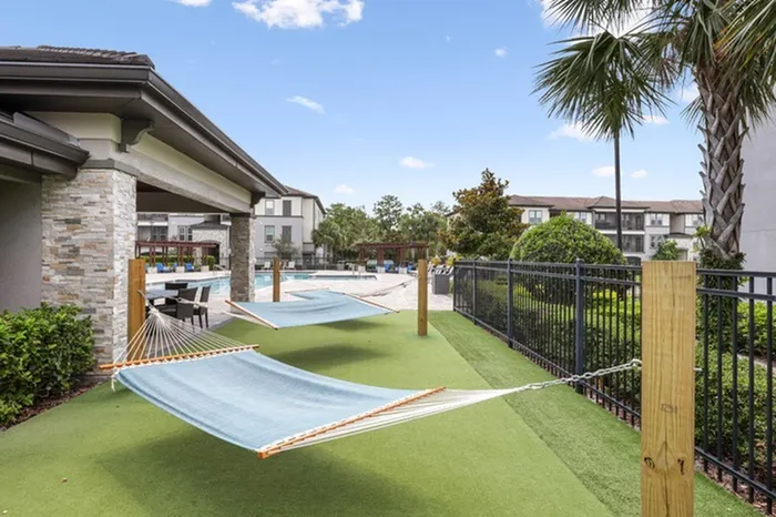 A resort-style artificial turf area with three hammocks at Lantower Grande Pines