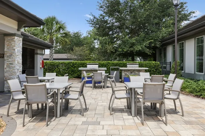 A sunny, outdoor seating area with two stainless steel grills at Lantower Grande Pines.