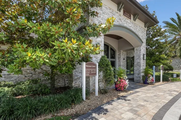 Welcome Center entrance at Lantower Grande Pines with pink and white flowers next to the large front doors.