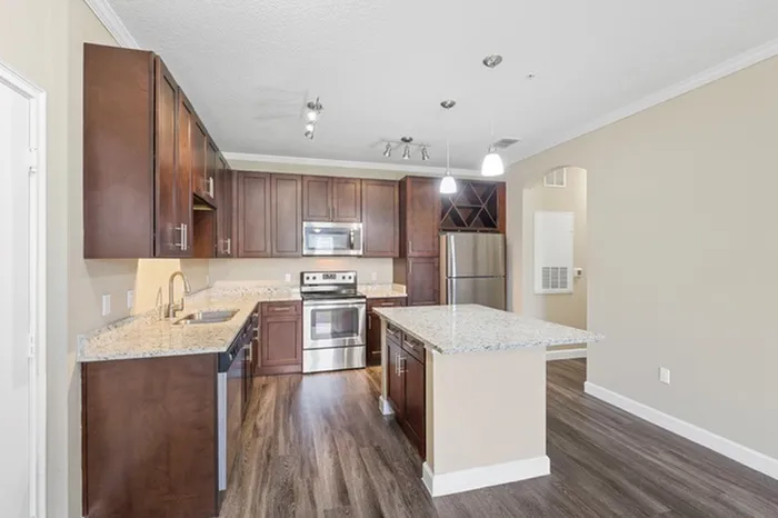 A kitchen with espresso wood cabinetry, wood-style flooring, a kitchen island with a granite countertop, Energy Star Stainless Steel