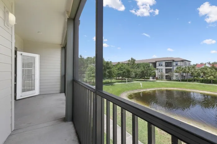 A long and spacious balcony with wooden railings and a view of a pond and trees at Lantower Grande Pines.