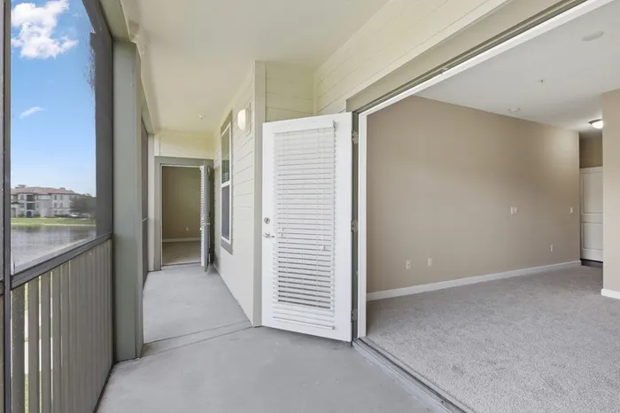 Long and spacious balcony with a door to the carpeted living room and a French door set to the bedroom open at Lantower Grande Pines.