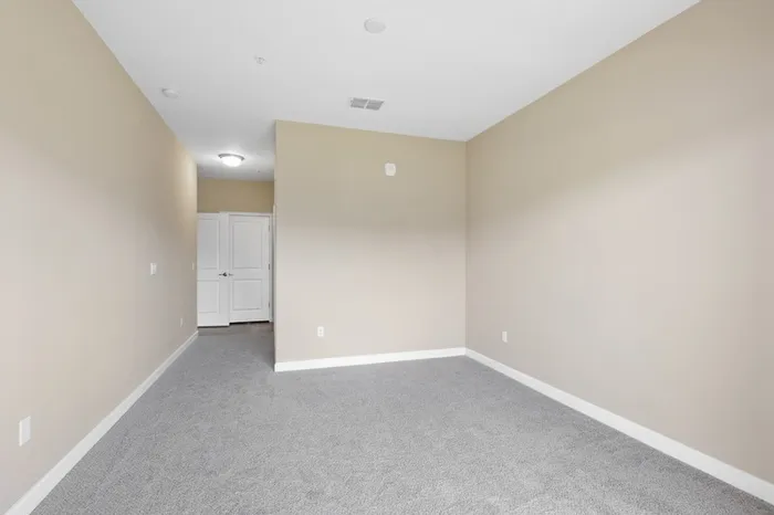 A carpeted, spacious bedroom with cream walls at Lantower Grande Pines.