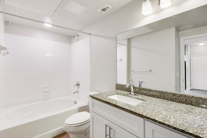 Apartment Bathroom with granite countertops and square tiled shower and tub, at Lantower Edgewater