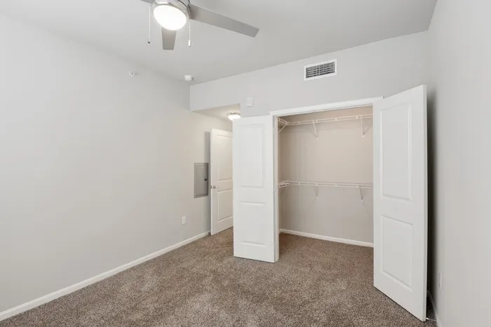 Carpet bedroom with a spacious closet, and a ceiling fan at Lantower Edgewater