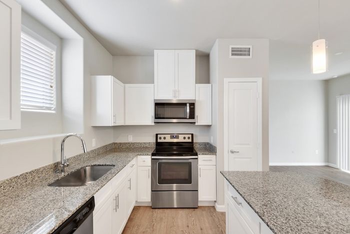 Kitchen and dining room with faux wood flooring, granite countertops, and Maytag stainless steel appliances at Lantower Edgewater