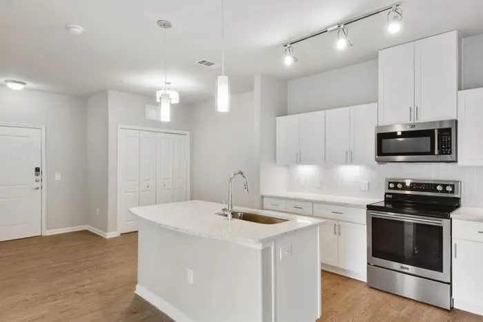 Kitchen and dining room with faux wood flooring, quartz countertops, and Maytag stainless steel appliances at Lantower Edgewater