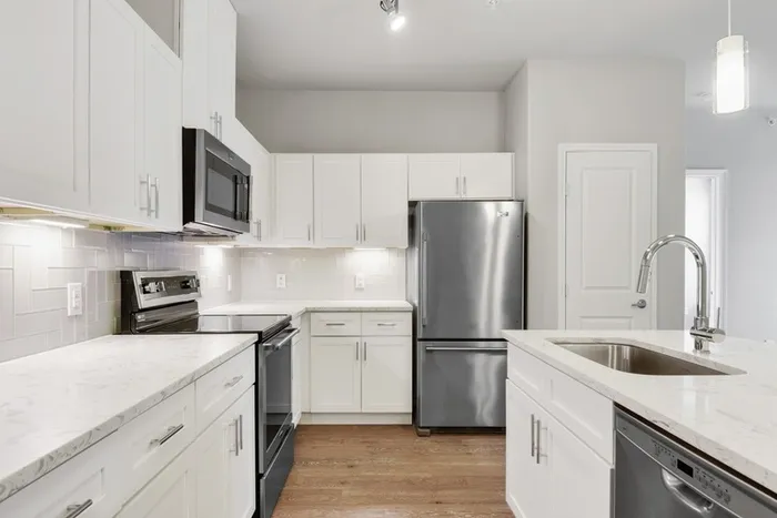 Kitchen and dining room with faux wood flooring, quartz countertops, and Maytag stainless steel appliances at Lantower Edgewater