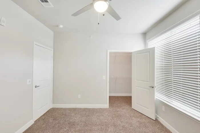 Bedroom with carpet flooring, a walk-in closet and natural lighting with a large window at Lantower Edgewater